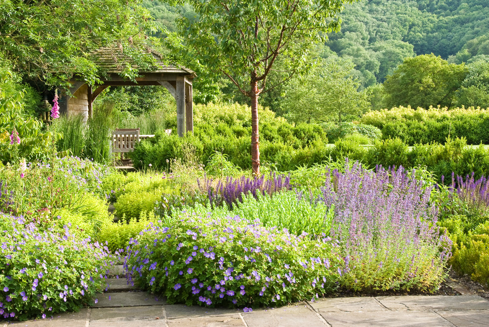 Photo of a large rural back full sun garden for summer in Sussex with natural stone paving.