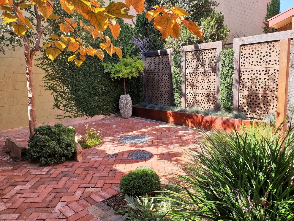 Exemple d'un petit jardin sur cour éclectique l'automne avec une exposition ensoleillée et des pavés en brique.