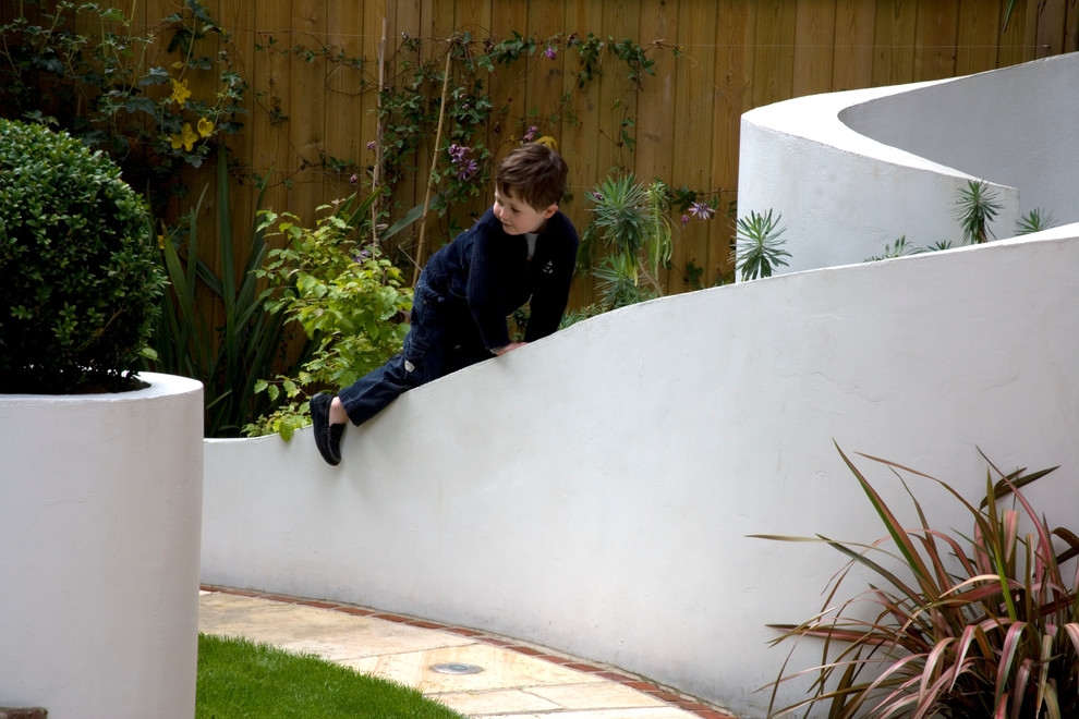 Photo of a large contemporary back formal garden in London with natural stone paving.