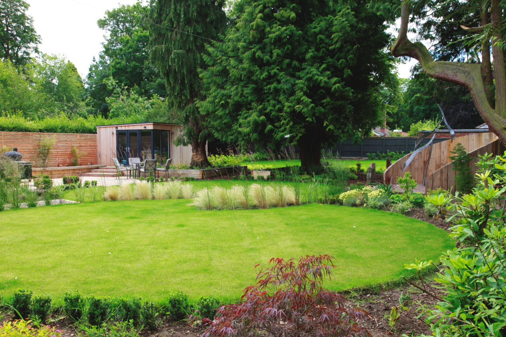 Imagen de jardín actual de tamaño medio en patio trasero con jardín francés y adoquines de piedra natural