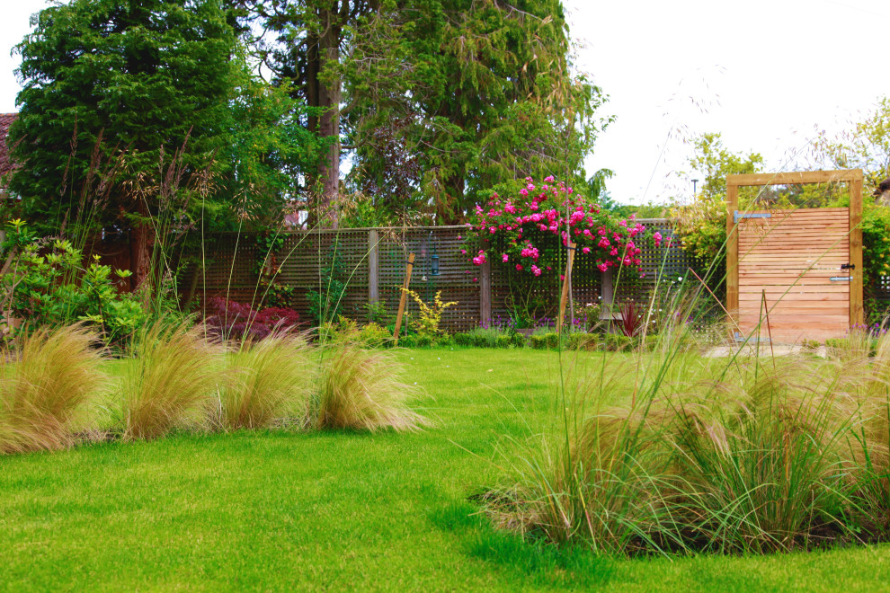 Diseño de jardín actual de tamaño medio en patio trasero con jardín francés y adoquines de piedra natural
