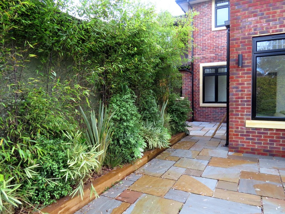 Medium sized contemporary back formal partial sun garden in London with natural stone paving.