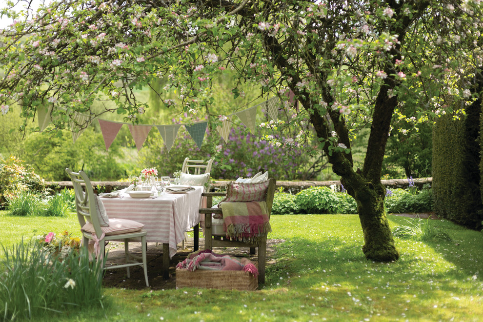 Diseño de jardín romántico grande en primavera en patio trasero con exposición reducida al sol y adoquines de piedra natural