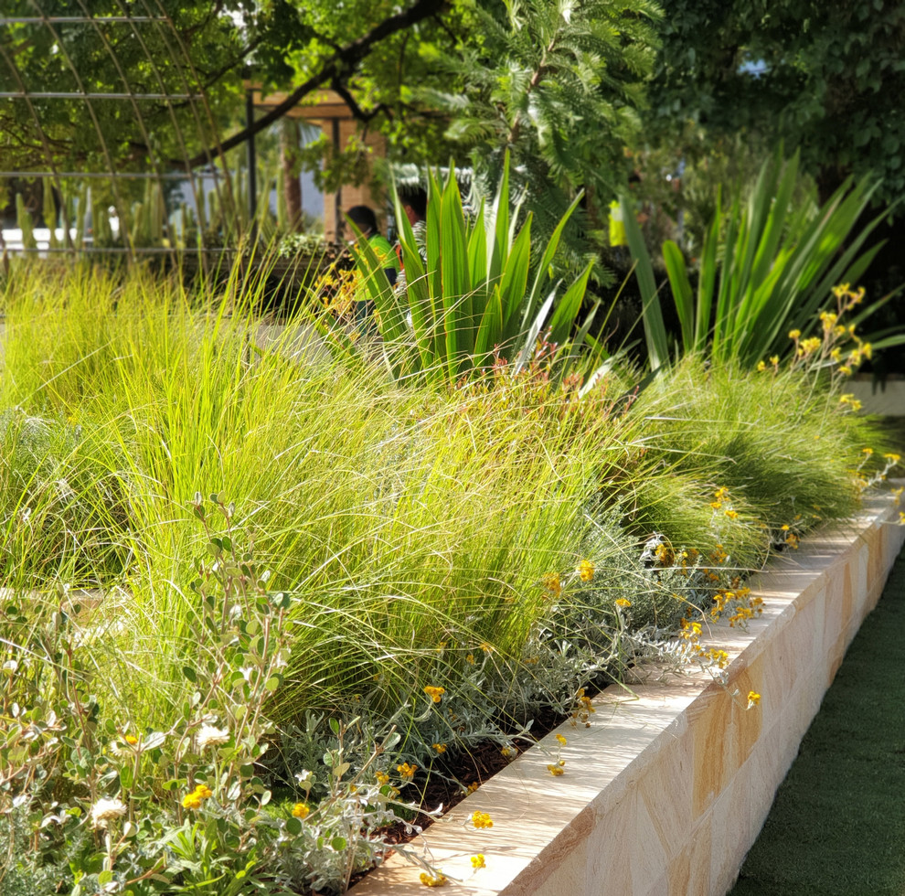 Imagen de jardín de secano contemporáneo de tamaño medio en verano en patio trasero con exposición total al sol, adoquines de piedra natural y brasero
