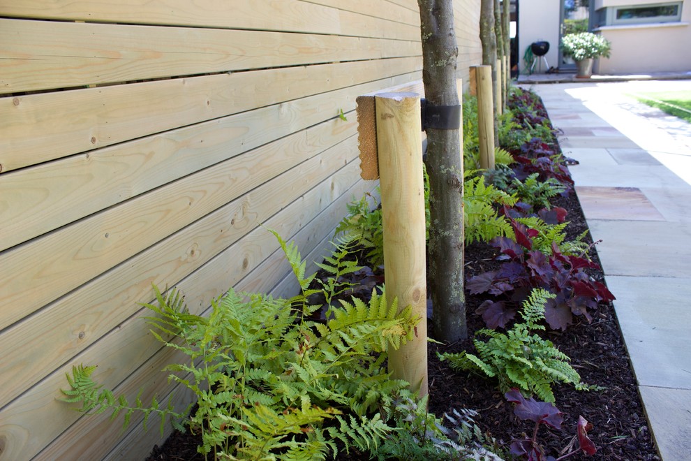 Idée de décoration pour un grand jardin arrière design l'été avec une exposition ensoleillée, des pavés en pierre naturelle et une clôture en bois.