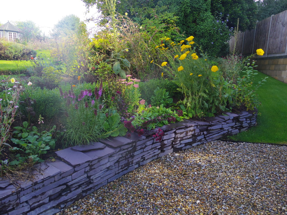 Стильный дизайн: большой солнечный регулярный сад на склоне в стиле кантри с подпорной стенкой, хорошей освещенностью и покрытием из каменной брусчатки - последний тренд
