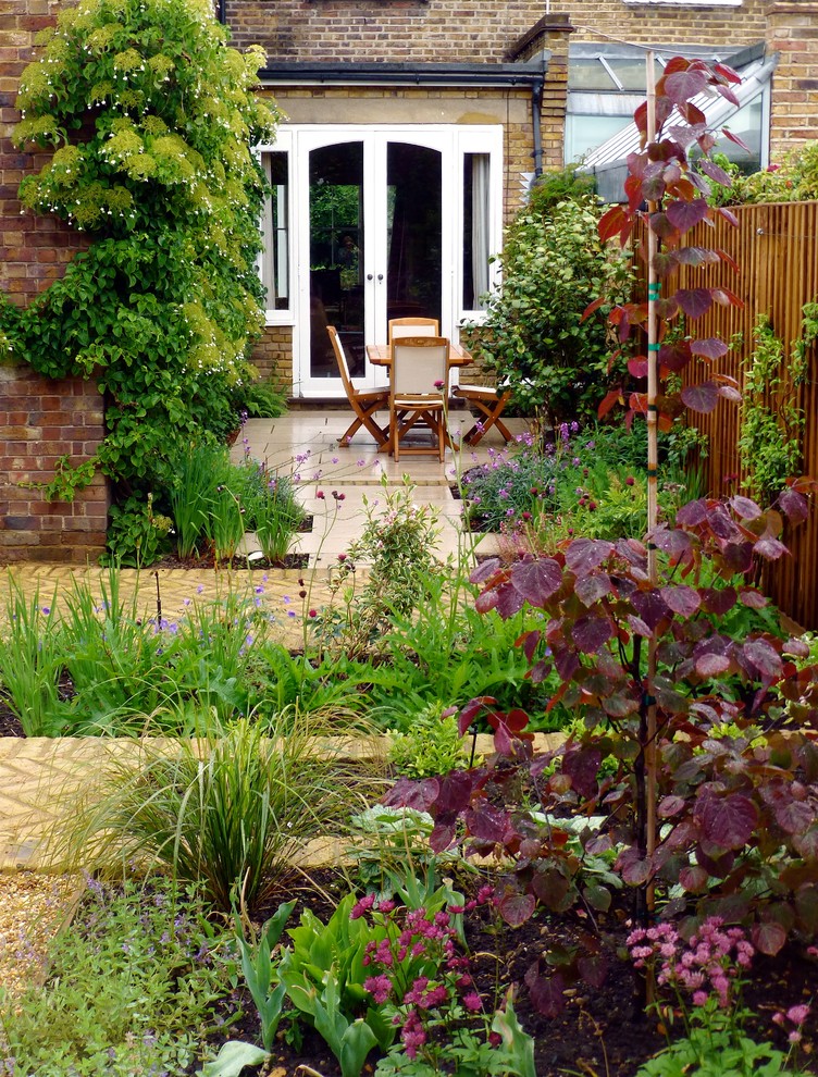 Small classic back full sun garden for summer in London with natural stone paving.