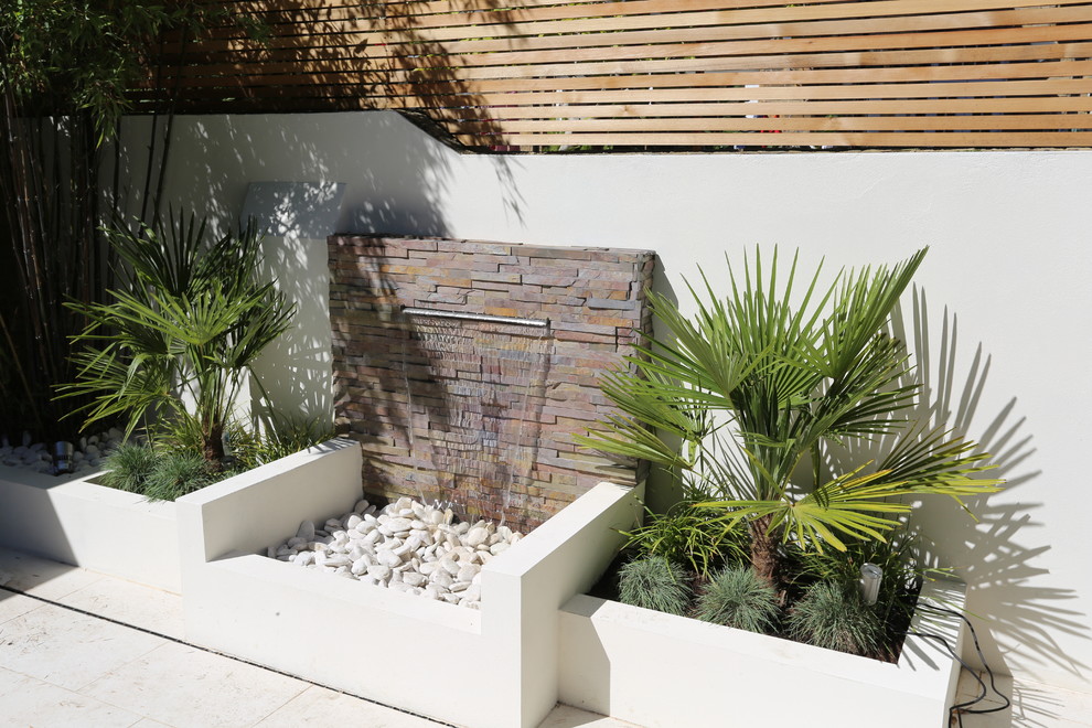 Foto di un piccolo giardino formale contemporaneo esposto a mezz'ombra dietro casa in primavera con fontane e pavimentazioni in pietra naturale