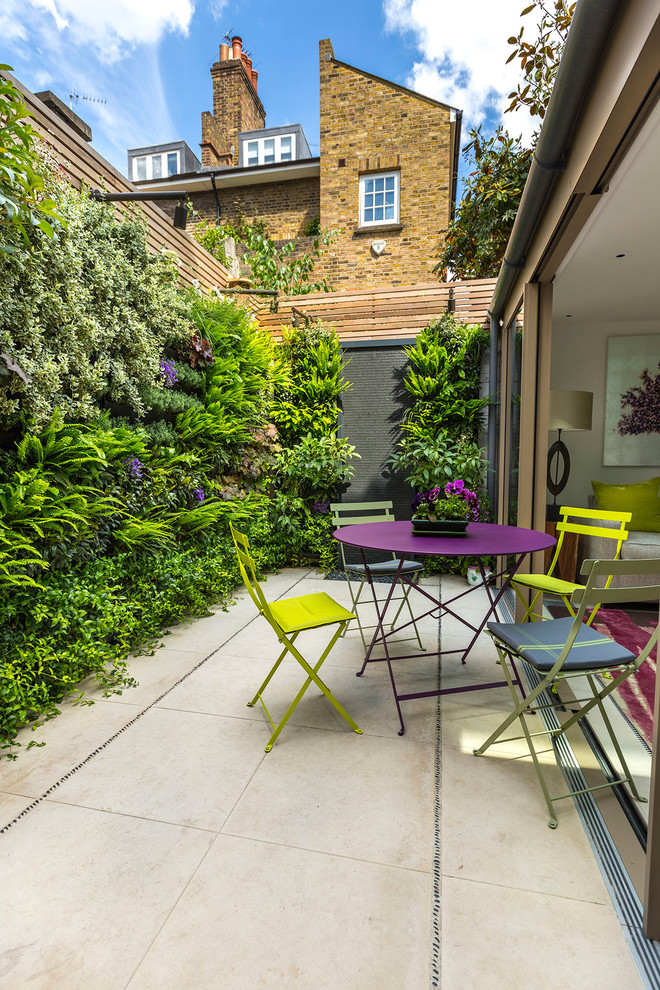 This is an example of a small contemporary back partial sun garden for summer in London with a living wall and natural stone paving.
