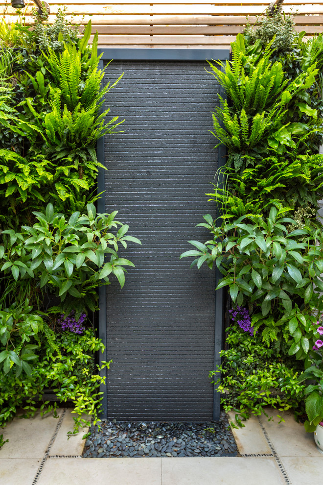 Design ideas for a small contemporary back partial sun garden for summer in London with a living wall and natural stone paving.