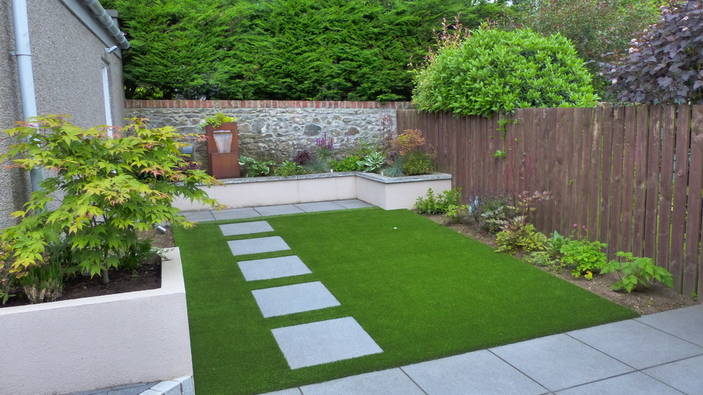 На фото: маленький тенистый регулярный сад на заднем дворе в современном стиле с подпорной стенкой и мощением тротуарной плиткой для на участке и в саду с