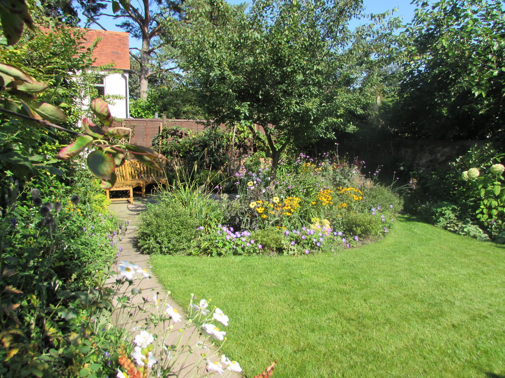 Exempel på en liten lantlig trädgård i delvis sol på sommaren, med en fontän och naturstensplattor
