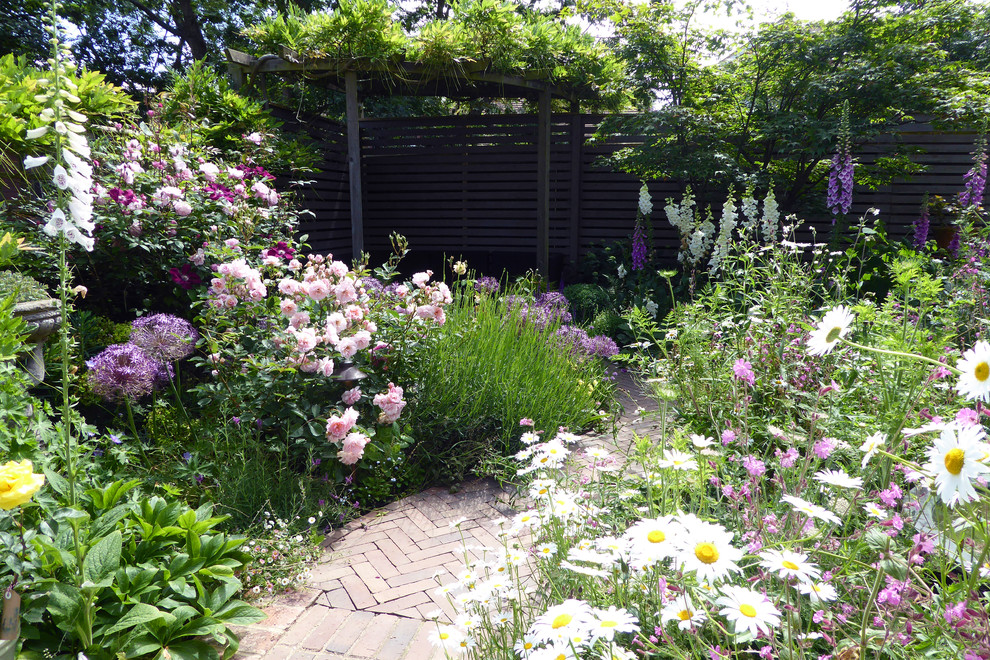 Kleiner Landhausstil Gartenweg im Sommer, hinter dem Haus mit direkter Sonneneinstrahlung und Pflastersteinen in Hertfordshire