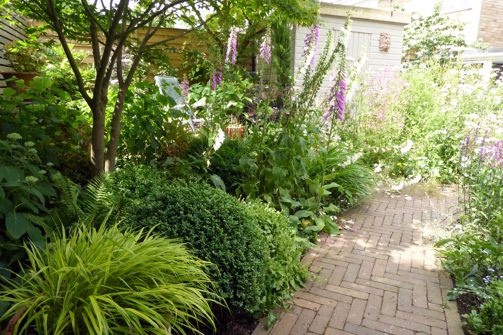 This is an example of a small traditional courtyard xeriscape partial sun garden for summer in Hertfordshire with a garden path and brick paving.