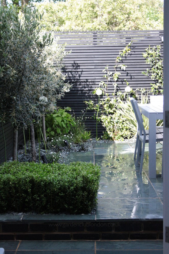 Aménagement d'un petit jardin arrière contemporain l'été avec une exposition partiellement ombragée et des pavés en pierre naturelle.