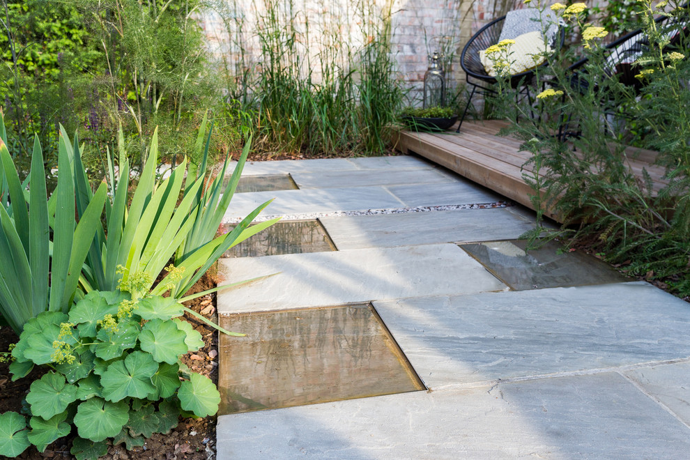 Photo of a mid-sized contemporary backyard stone landscaping in London.