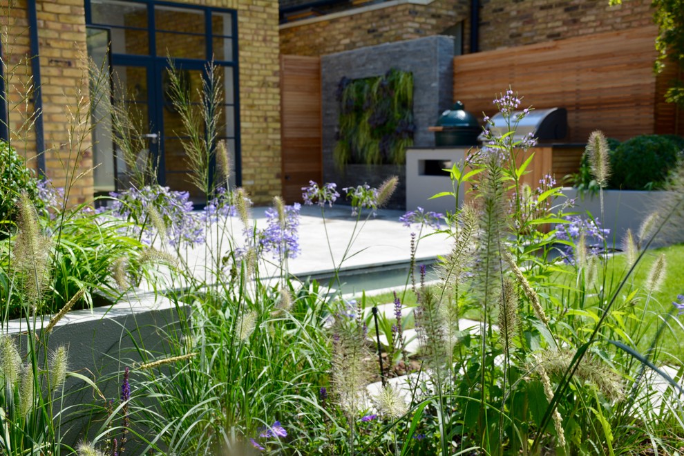 Medium sized contemporary back full sun garden for summer in London with a pond and natural stone paving.