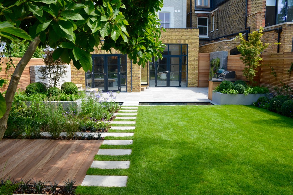 Design ideas for a mid-sized contemporary full sun backyard stone pond in London for summer.