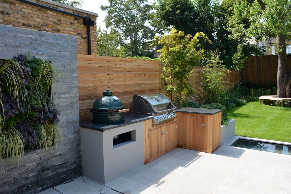 Medium sized contemporary back full sun garden for summer in London with a pond and natural stone paving.