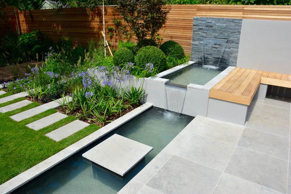 Design ideas for a medium sized contemporary back full sun garden for summer in London with a pond and natural stone paving.