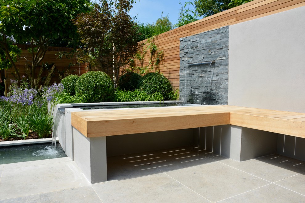 Photo of a medium sized contemporary back full sun garden for summer in London with a pond and natural stone paving.