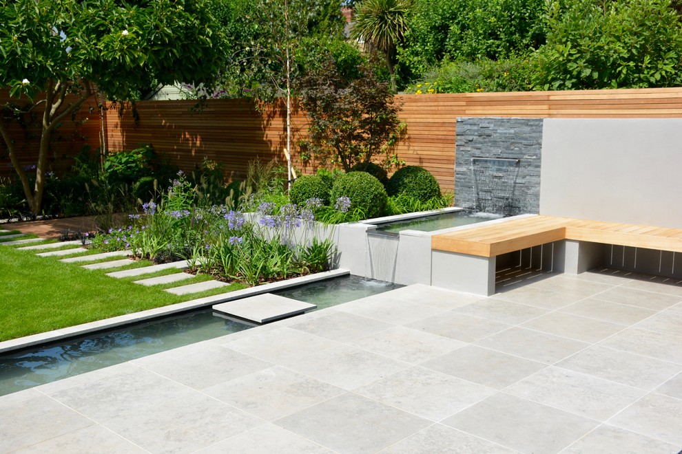 Modelo de jardín contemporáneo de tamaño medio en verano en patio trasero con estanque, exposición total al sol y adoquines de piedra natural