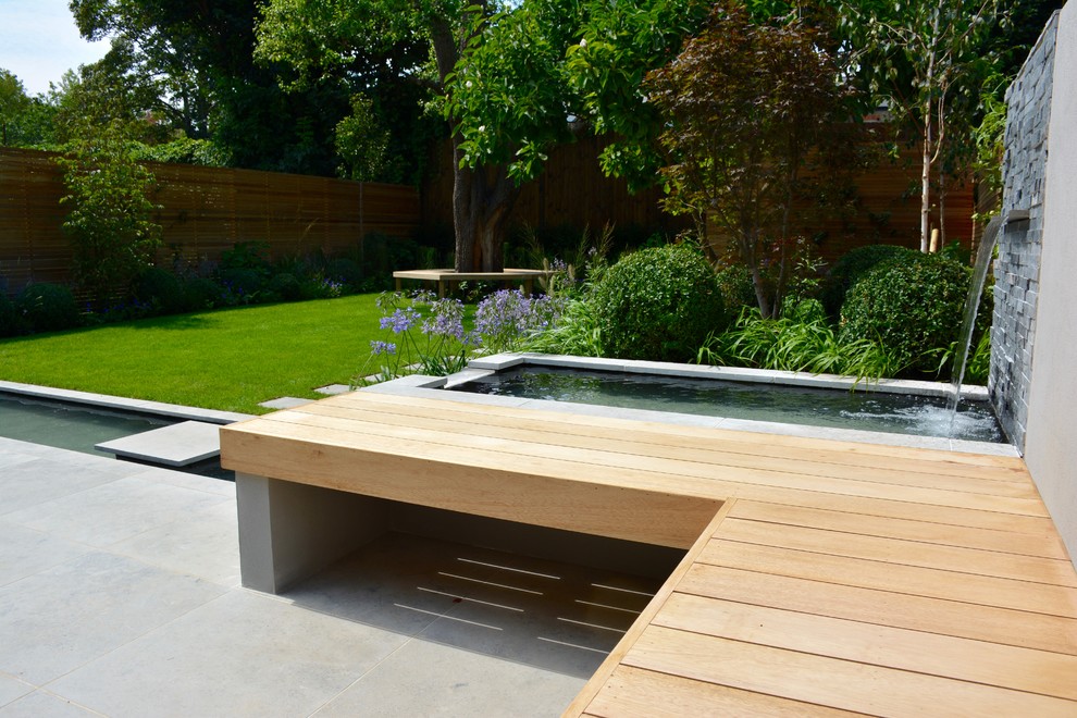 Inspiration for a medium sized contemporary back full sun raised pond for summer in London with natural stone paving.