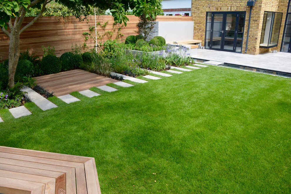Medium sized contemporary back full sun garden for summer in London with a pond and natural stone paving.