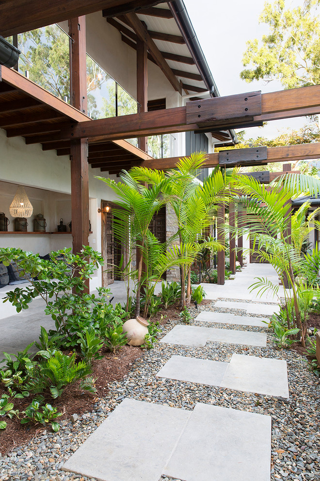 Bild på en tropisk trädgård framför huset och gångväg