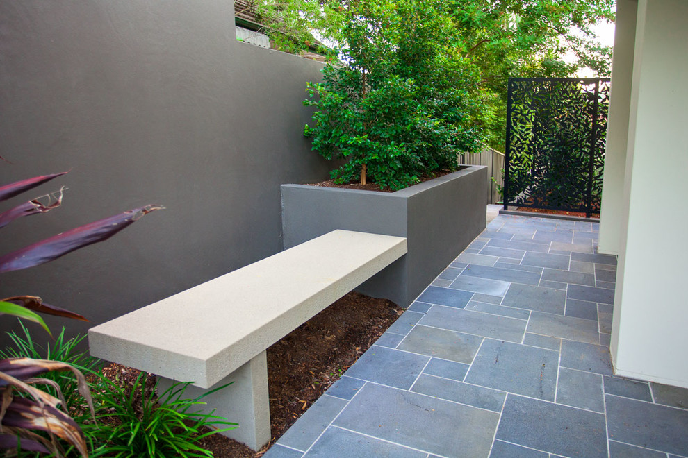 This is an example of a medium sized modern side formal garden in Brisbane with natural stone paving.