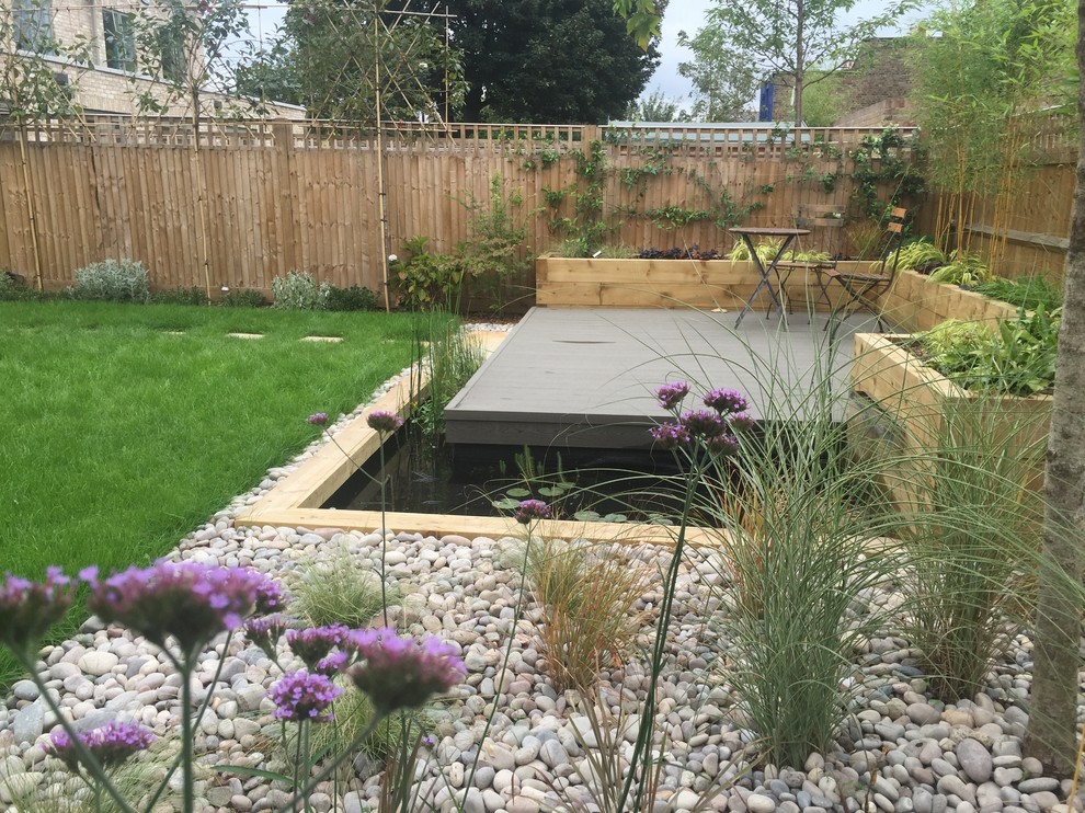 This is an example of a medium sized contemporary back full sun garden for summer in London with a water feature and decking.