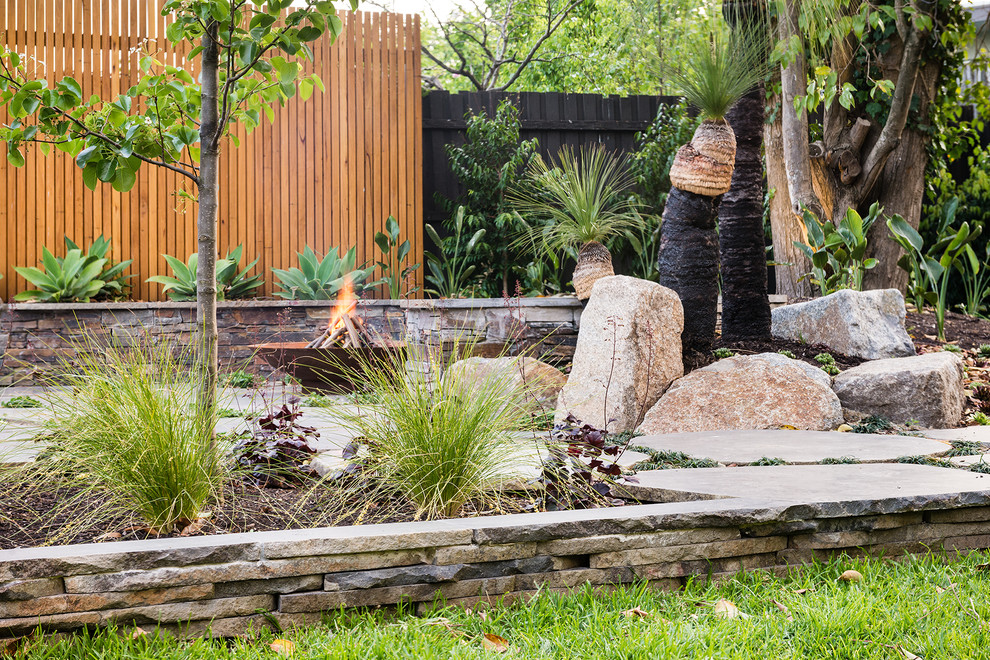 Diseño de jardín moderno grande en patio trasero con brasero, exposición reducida al sol y adoquines de piedra natural