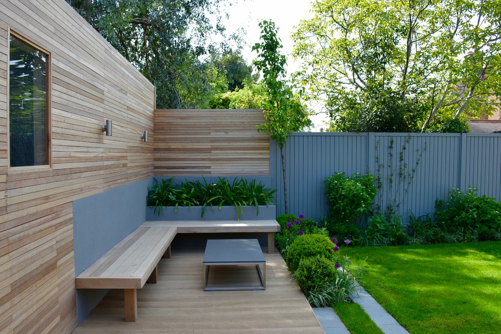 Inspiration pour un jardin arrière design de taille moyenne avec une exposition ensoleillée et une terrasse en bois.