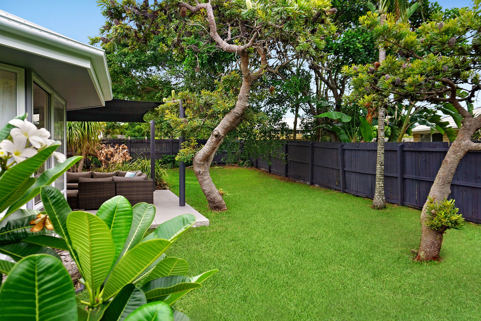 This is an example of a nautical back garden in Sunshine Coast with concrete paving.