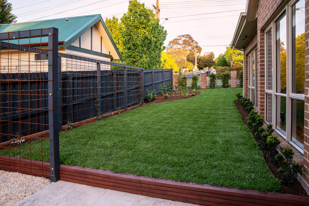Photo of a mid-sized contemporary partial sun backyard stone landscaping in Melbourne for spring.