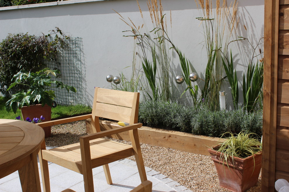 Geometrischer, Kleiner Eklektischer Garten im Sommer, hinter dem Haus mit Kübelpflanzen, direkter Sonneneinstrahlung, Natursteinplatten und Steinzaun in Dublin