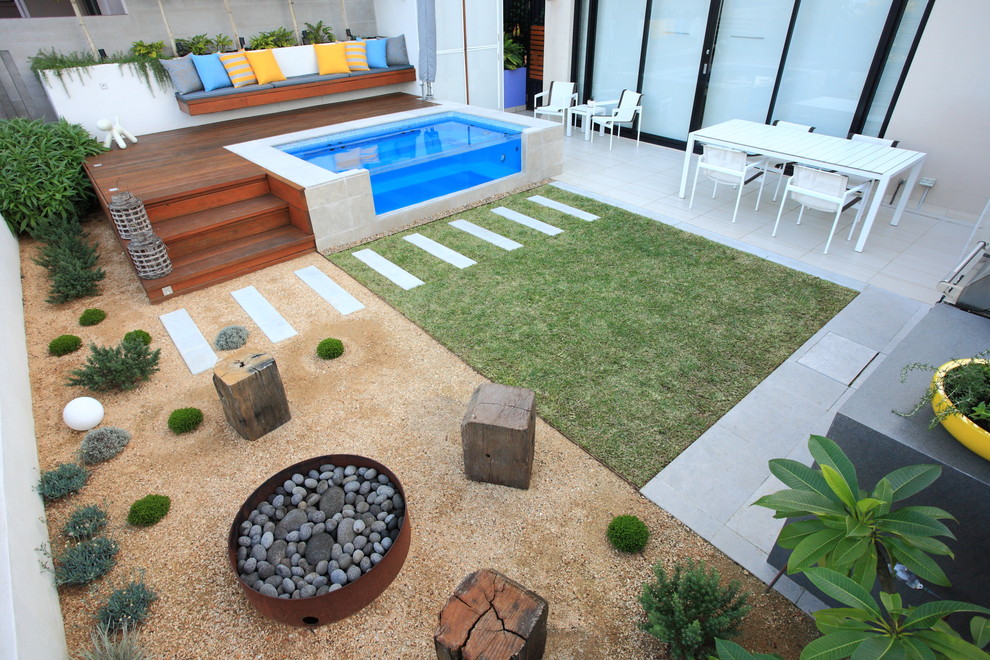 Idée de décoration pour un jardin arrière minimaliste de taille moyenne et l'été avec un foyer extérieur, une exposition ensoleillée et du gravier.