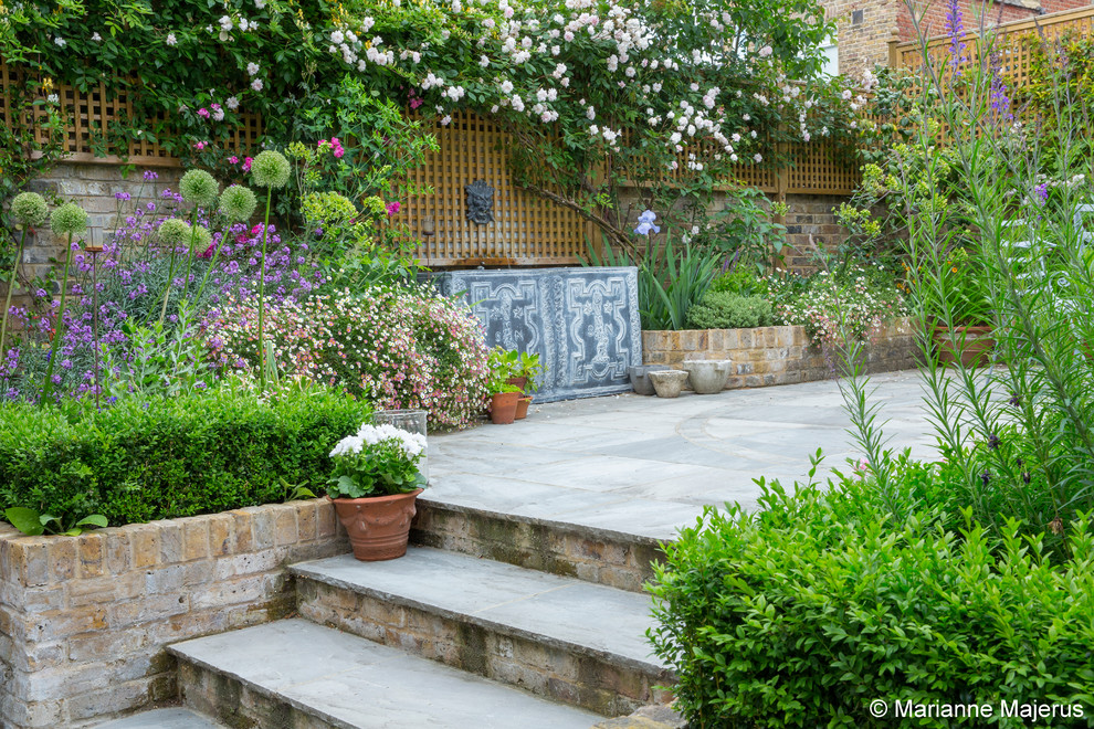 Mittelgroßer, Halbschattiger Klassischer Garten im Sommer, hinter dem Haus mit Wasserspiel und Natursteinplatten in London