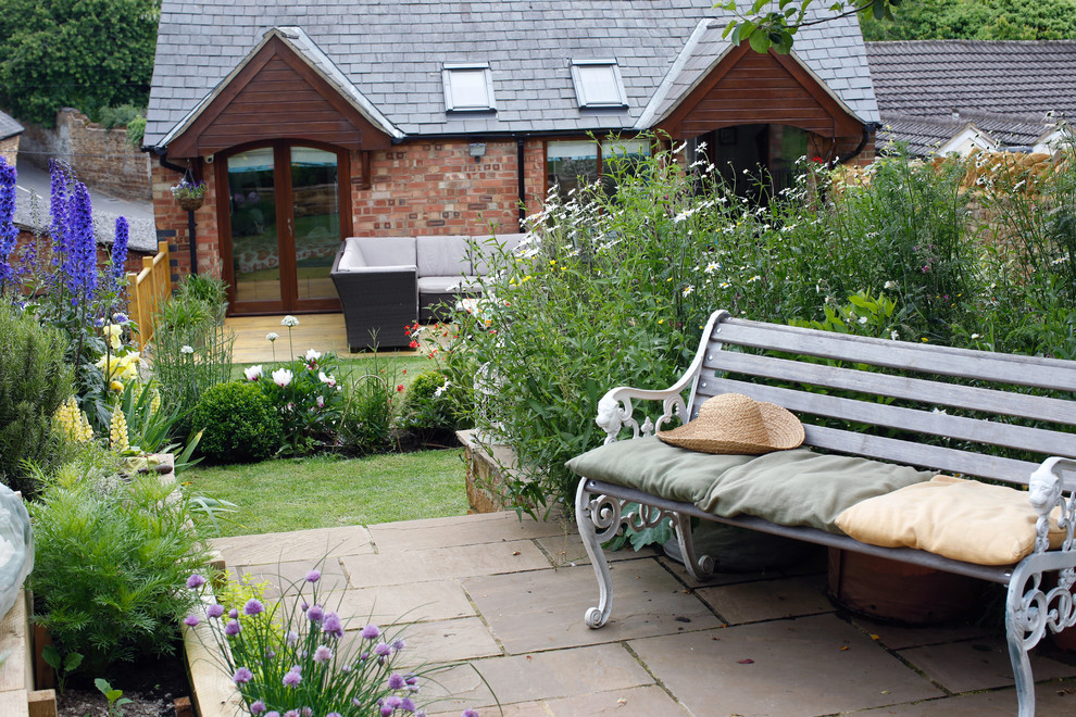 Esempio di un giardino country esposto in pieno sole di medie dimensioni e dietro casa in estate con un muro di contenimento e pavimentazioni in pietra naturale