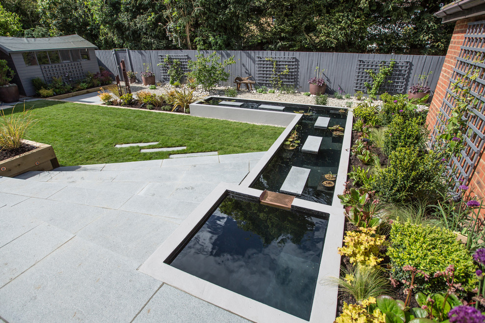 Immagine di un laghetto da giardino contemporaneo esposto a mezz'ombra di medie dimensioni con pavimentazioni in pietra naturale