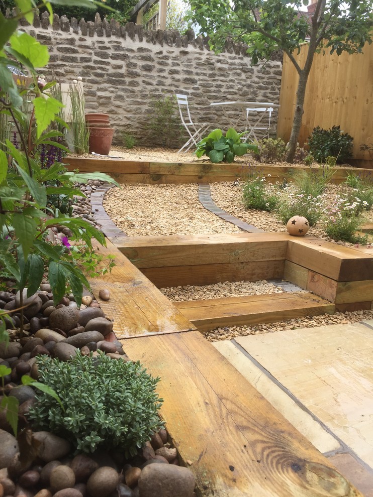 Idee per un piccolo giardino contemporaneo esposto in pieno sole dietro casa in estate con un muro di contenimento e ghiaia