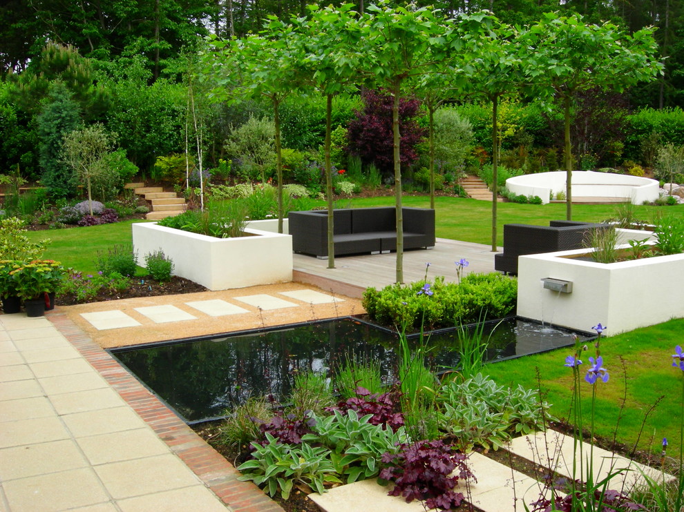 Photo of a large contemporary back formal full sun raised pond in Surrey with concrete paving.