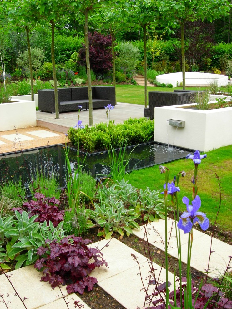На фото: большой солнечный регулярный сад на заднем дворе в современном стиле с хорошей освещенностью и мощением тротуарной плиткой с