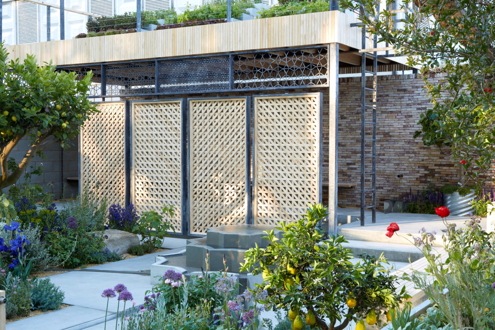 Diseño de jardín de secano actual pequeño en primavera en patio con fuente, exposición total al sol y adoquines de hormigón