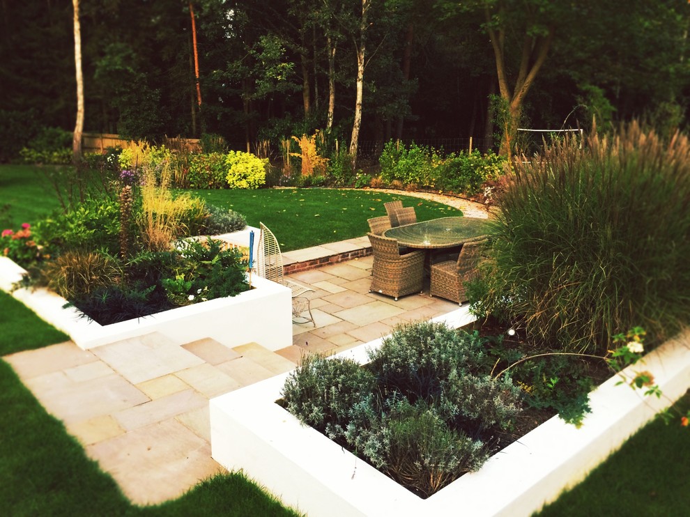 Large contemporary back partial sun garden for autumn in Surrey with natural stone paving.