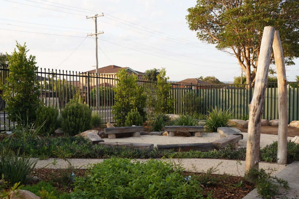 Ispirazione per un giardino xeriscape design esposto in pieno sole di medie dimensioni e davanti casa con uno spazio giochi, graniglia di granito e recinzione in metallo