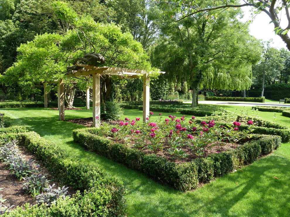 На фото: регулярный сад среднего размера в классическом стиле с клумбами и с перголой с