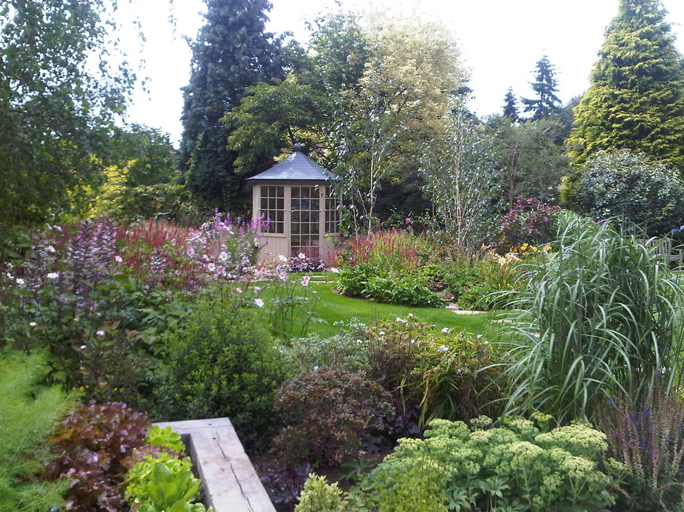 Modelo de jardín tradicional de tamaño medio en patio trasero con jardín francés, exposición parcial al sol y adoquines de piedra natural