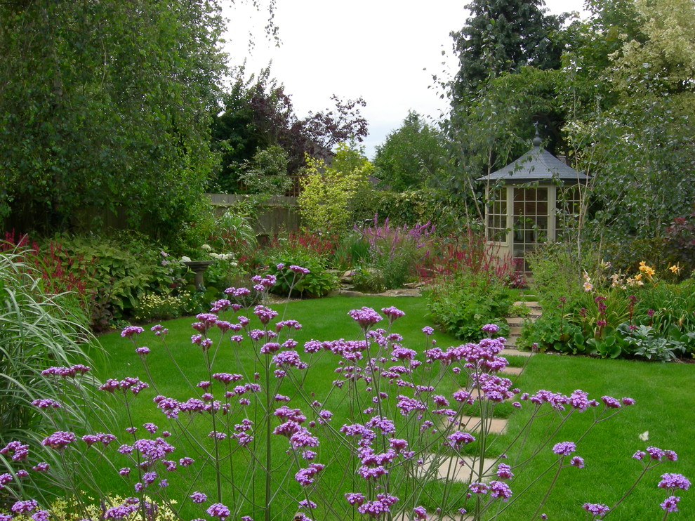 Modelo de jardín clásico de tamaño medio en patio trasero con jardín francés, exposición parcial al sol y adoquines de piedra natural