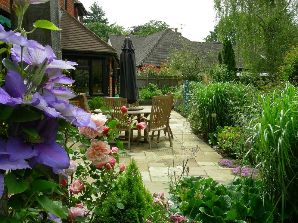 This is an example of a medium sized traditional back formal partial sun garden in Surrey with natural stone paving.